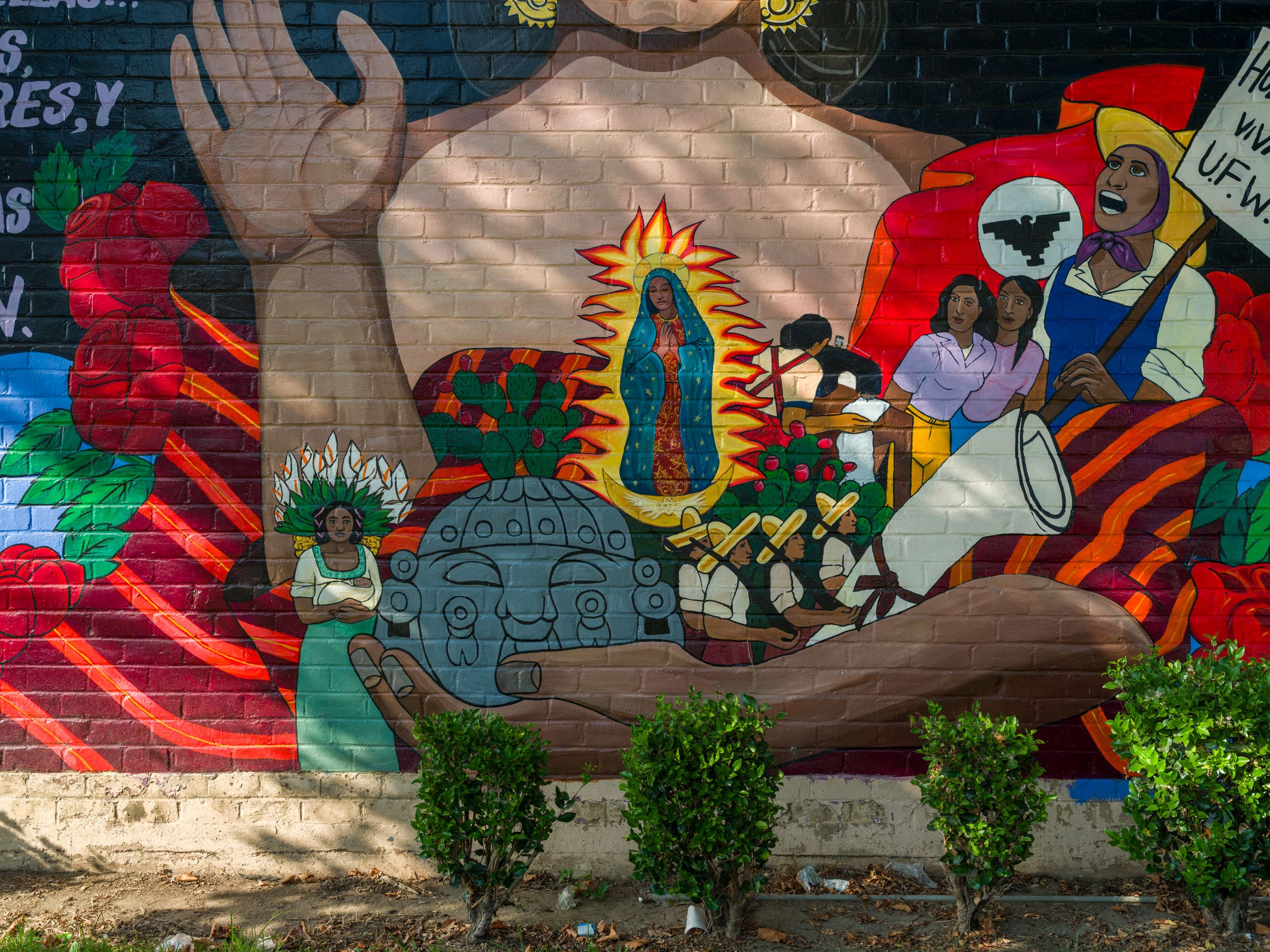 Detail imagery is being held in the arms of a female figure. This includes a labor rights protestor and the Aztec goddess sculpture.