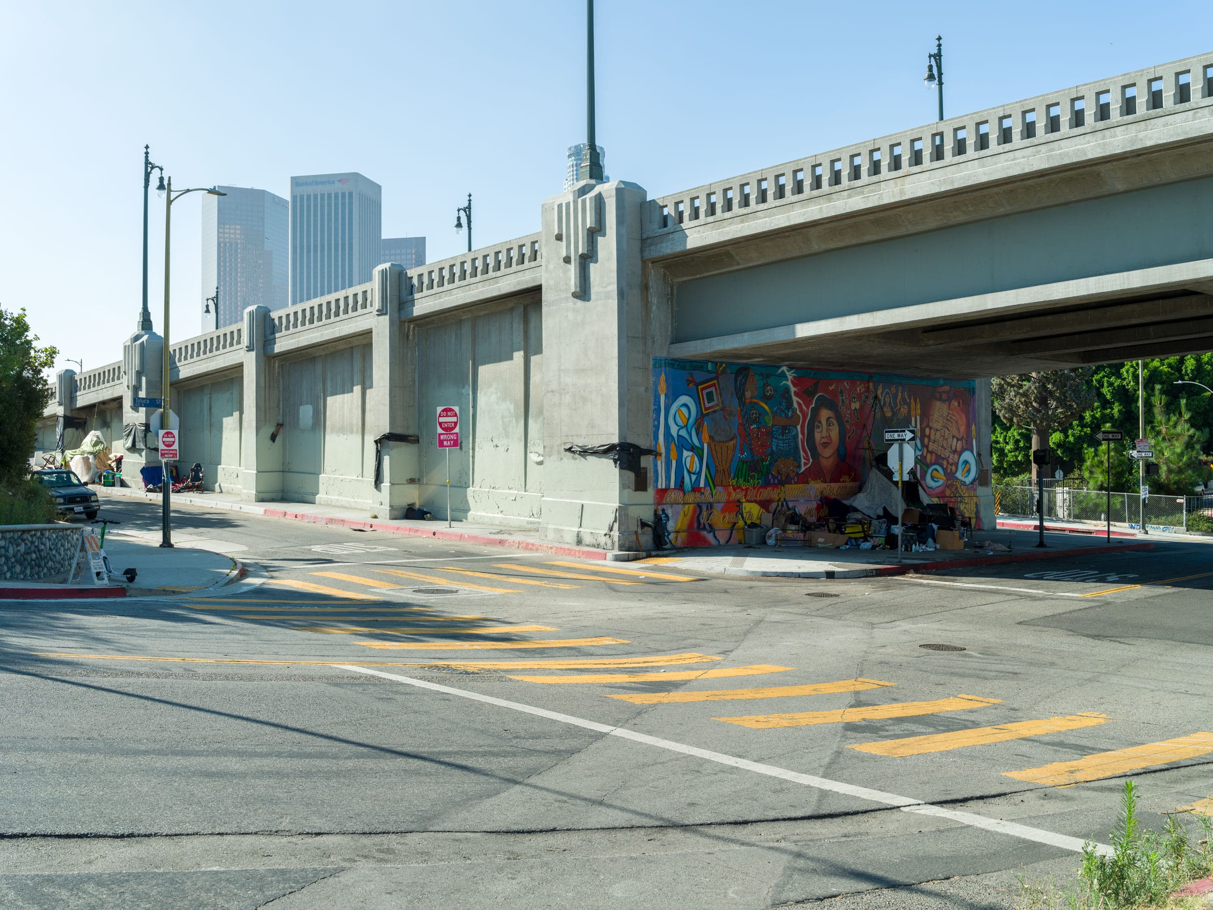 A full view of the exit ramp of a freeway and the Yreina Cervantez mural under the overpass.