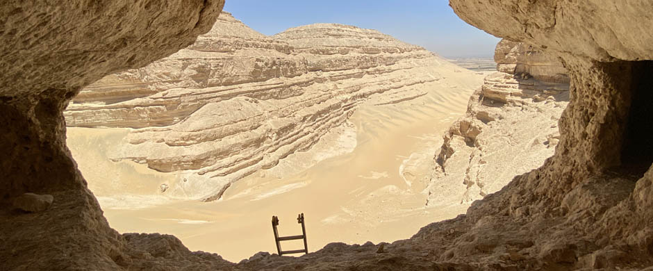 General view from an excavation in Egypt with a ladder in the foreground and a desert type atmosphere in the background.