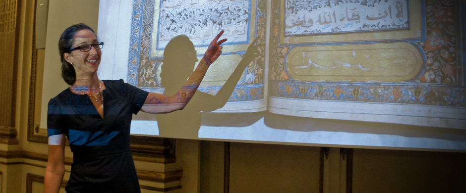 A recent lecturer gesturing toward a slide of an illuminated manuscript