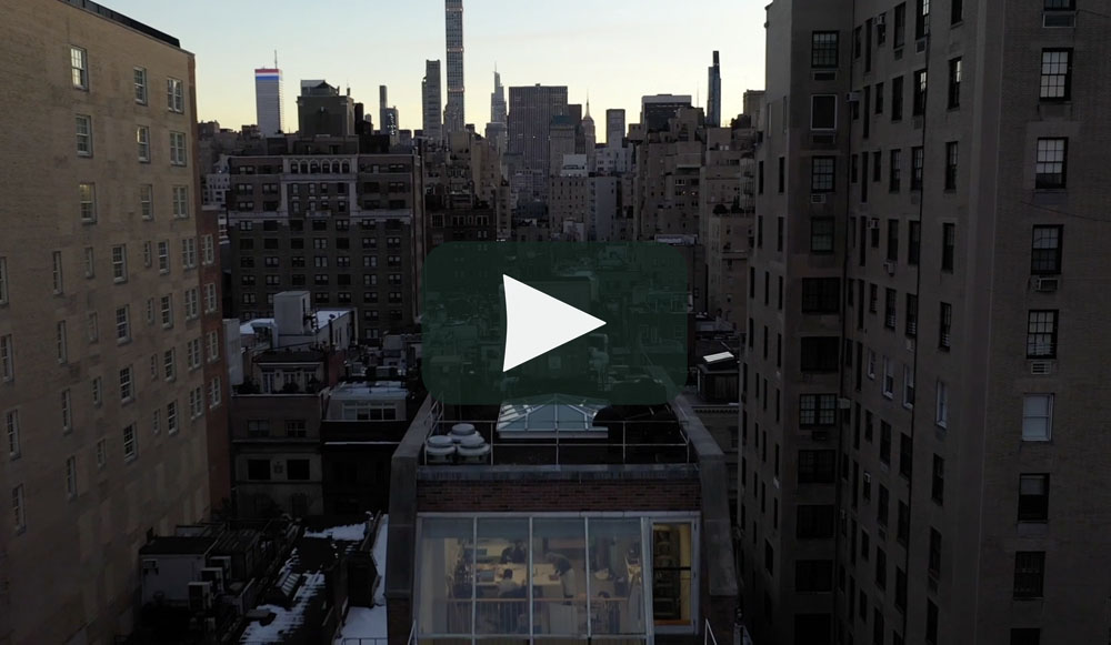 footage from a drone showing the top of the Conservation Cente building and the New York skyline facing downtown in the background.
