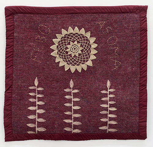 Textile with red fabric and beige flowering symbols with text that reads 'Febo Asoma'