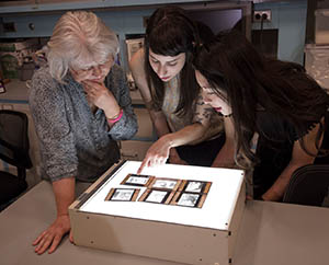 Students and professor hovering over a lighttable looking at transparencies