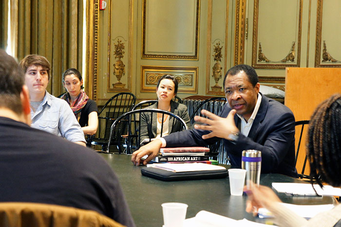Photo of Okwei Enwezor speaking with students seated at a round table