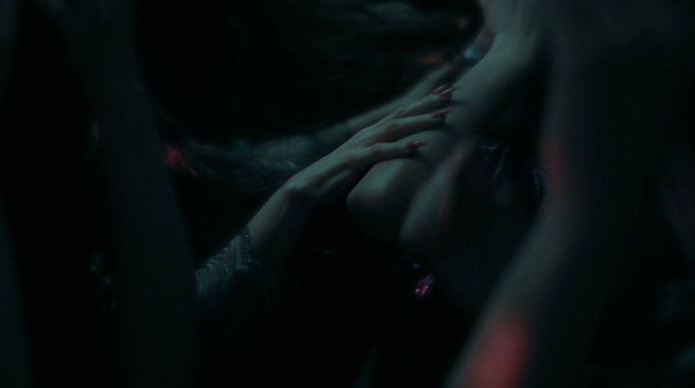 Hands resting on body in a dark room.